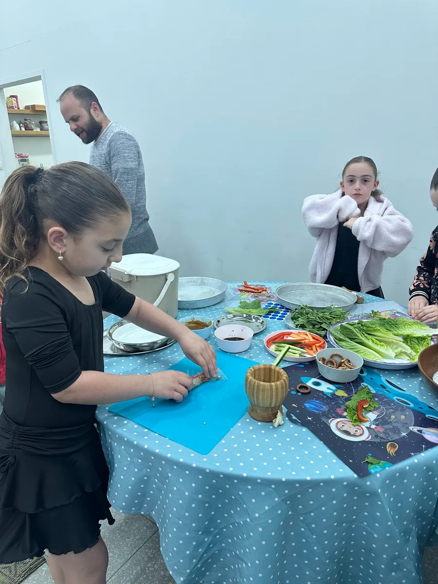 ילדה חותכת ירקות בעמדת עבודה