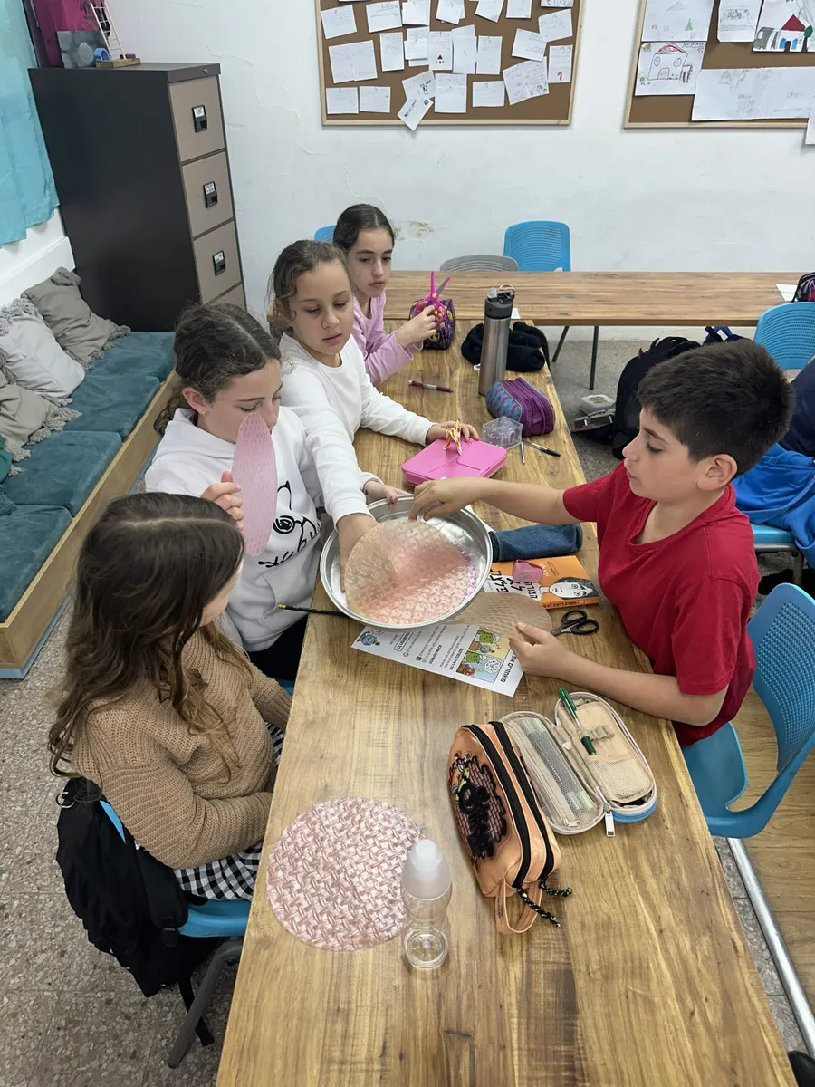 קבוצת תלמידים עובדת סביב שולחן בכיתה